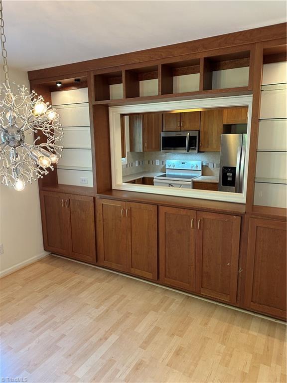 135 Plantation Place Ln, Mount Airy, NC 27030 - kitchen with appliances with stainless steel finishes, light wood-type flooring, brown cabinets, and a chandelier