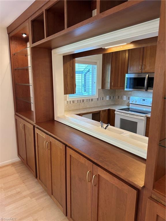 135 Plantation Place Ln, Mount Airy, NC 27030 - kitchen with electric stove, stainless steel microwave, light wood finished floors, decorative backsplash, and brown cabinets