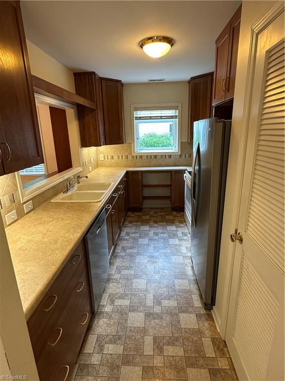 135 Plantation Place Ln, Mount Airy, NC 27030 - kitchen featuring stainless steel appliances, tasteful backsplash, light countertops, and brick patterned flooring