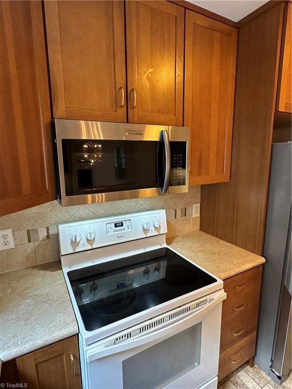 135 Plantation Place Ln, Mount Airy, NC 27030 - kitchen featuring stainless steel appliances, brown cabinets, backsplash, and light countertops