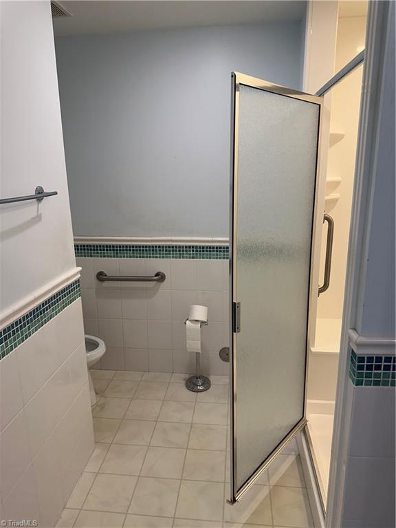 135 Plantation Place Ln, Mount Airy, NC 27030 - full bathroom featuring tile patterned floors, a stall shower, tile walls, and a wainscoted wall