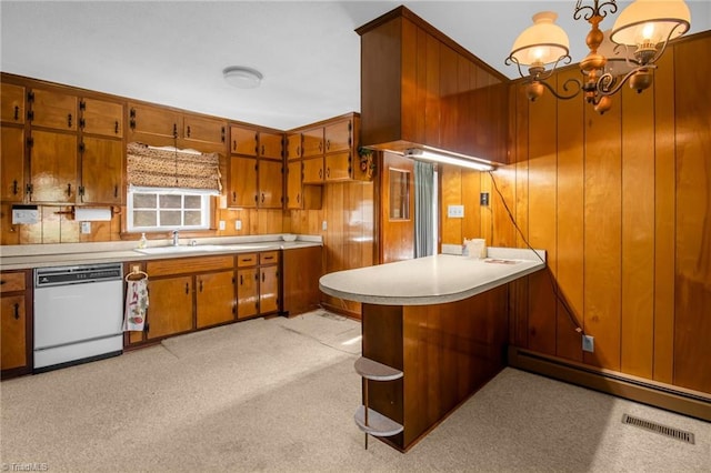 520 S Bunker Hill Rd, Colfax, NC 27235 - kitchen with dishwasher, brown cabinets, light countertops, a chandelier, and wooden walls