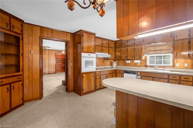 520 S Bunker Hill Rd, Colfax, NC 27235 - kitchen with white appliances, under cabinet range hood, light countertops, brown cabinetry, and wooden walls