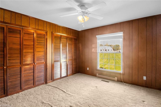 520 S Bunker Hill Rd, Colfax, NC 27235 - unfurnished bedroom featuring two closets, carpet, a baseboard heating unit, wooden walls, and a ceiling fan