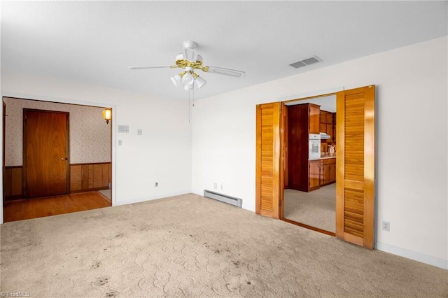 520 S Bunker Hill Rd, Colfax, NC 27235 - unfurnished room featuring a baseboard heating unit, carpet floors, a ceiling fan, and a wainscoted wall