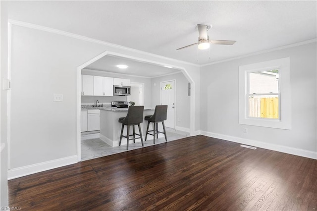 1908 Hilldale Dr, Burlington, NC 27215 - kitchen featuring appliances with stainless steel finishes, white cabinets, ornamental molding, a kitchen bar, and light wood finished floors