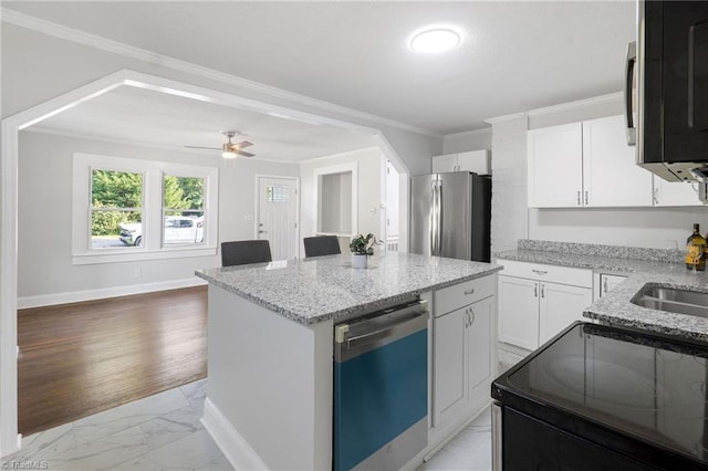 1908 Hilldale Dr, Burlington, NC 27215 - kitchen featuring appliances with stainless steel finishes, light marble finish floors, ornamental molding, a kitchen island, and light stone countertops
