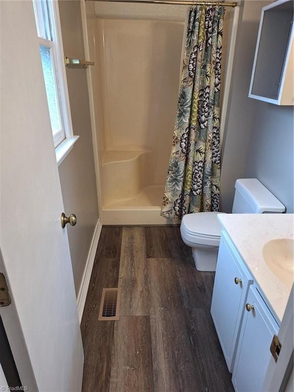 full bath with wood finished floors, curtained shower, toilet, and vanity