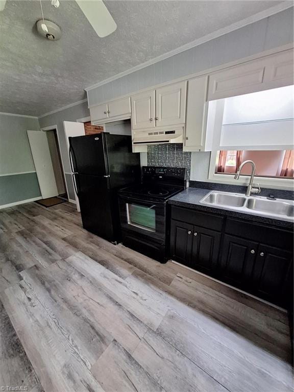 kitchen featuring black appliances, a sink, under cabinet range hood, ornamental molding, and light wood-type flooring