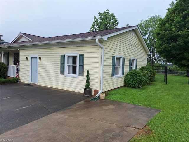view of side of home featuring a shingled roof and a patio