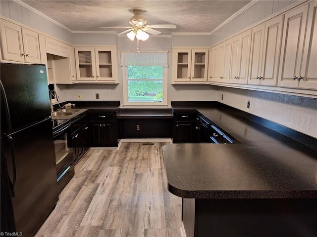 kitchen with black appliances, dark countertops, a ceiling fan, a sink, and light wood-style floors