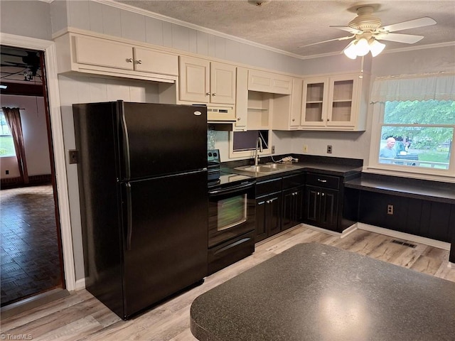 kitchen with black appliances, a sink, ornamental molding, under cabinet range hood, and dark countertops