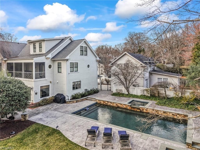 rear view of property featuring a fenced in pool, a sunroom, a patio area, fence, and an in ground hot tub