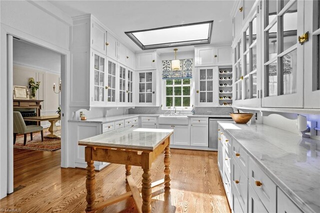 kitchen with white cabinets, pendant lighting, light wood-type flooring, and light stone countertops