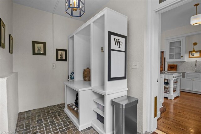 mudroom featuring dark wood-type flooring and an inviting chandelier