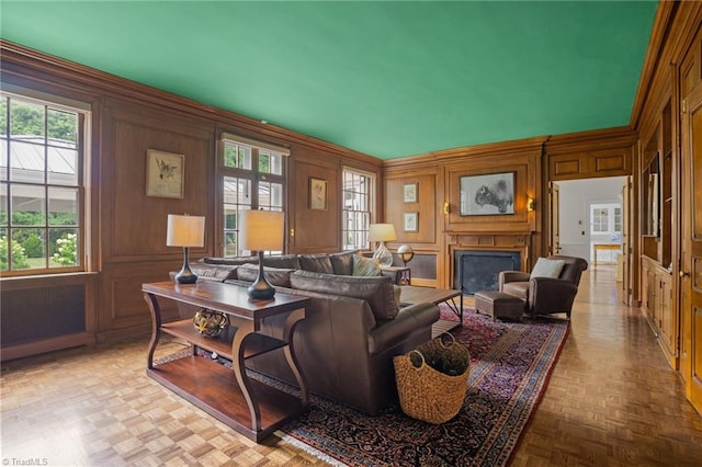 living room with light parquet floors, crown molding, wooden walls, and radiator