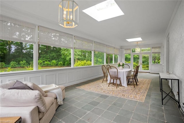 sunroom featuring plenty of natural light, an inviting chandelier, and a skylight