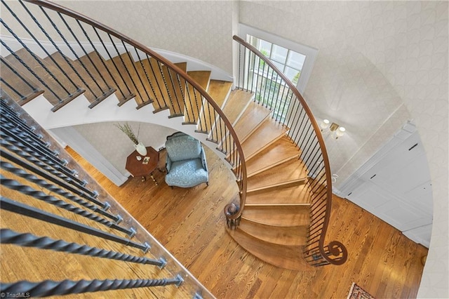 stairs with wood-type flooring and a towering ceiling