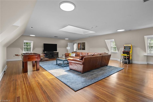 living room with vaulted ceiling with skylight and hardwood / wood-style flooring