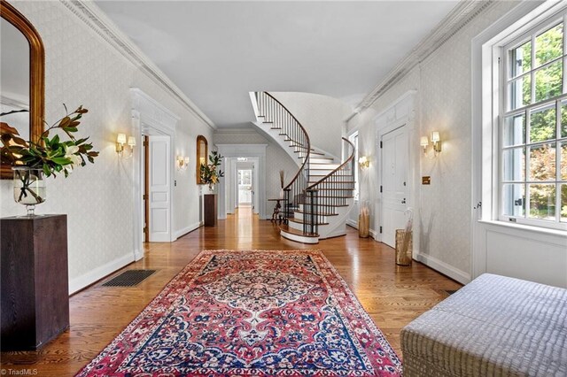 foyer entrance with wood-type flooring and crown molding