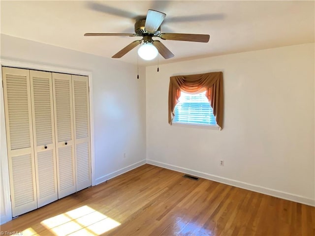 unfurnished bedroom with ceiling fan, light wood-type flooring, and a closet