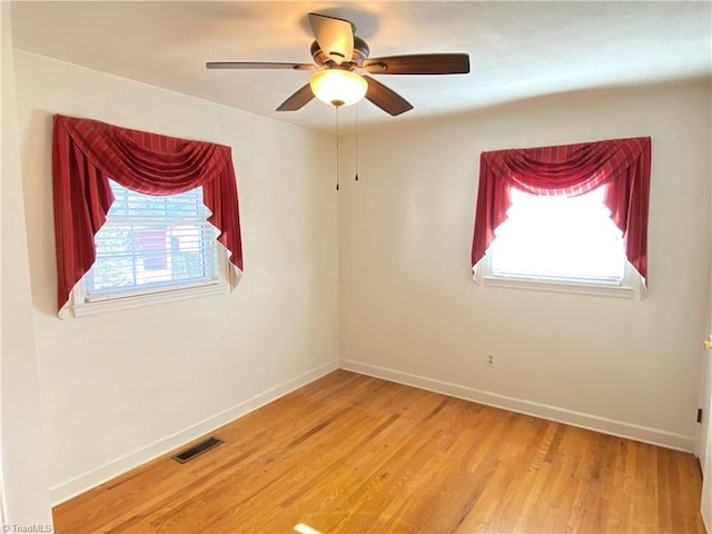 empty room with hardwood / wood-style floors, ceiling fan, and a healthy amount of sunlight