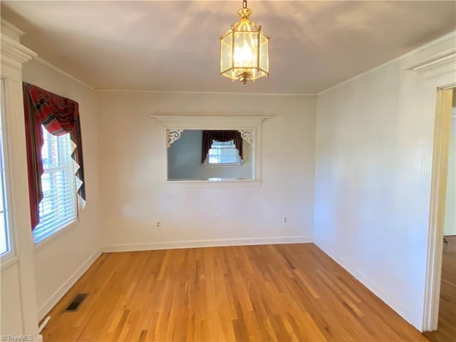 spare room with a chandelier and light wood-type flooring