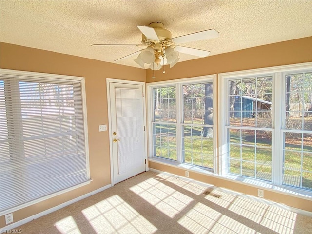 unfurnished sunroom with ceiling fan and a healthy amount of sunlight