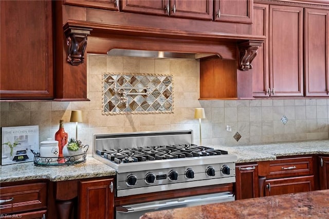 kitchen featuring light stone counters, decorative backsplash, and range