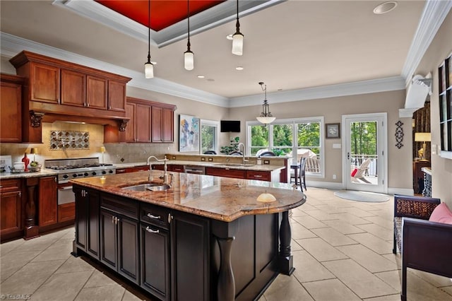 kitchen featuring premium range hood, sink, light stone counters, hanging light fixtures, and a center island with sink