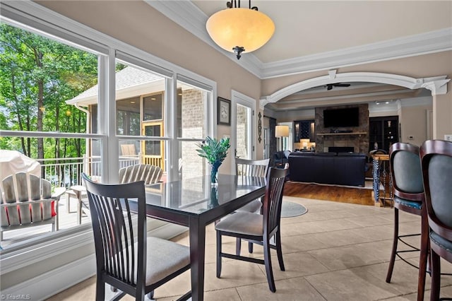 tiled dining room with ornamental molding, a large fireplace, and ceiling fan