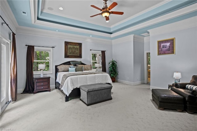 bedroom with ceiling fan, ornamental molding, a tray ceiling, and light carpet