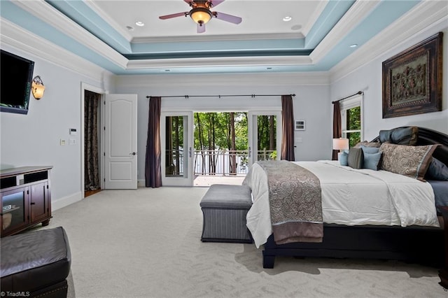 carpeted bedroom with ornamental molding, a tray ceiling, multiple windows, and access to outside