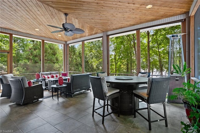 unfurnished sunroom with ceiling fan, wood ceiling, and a healthy amount of sunlight