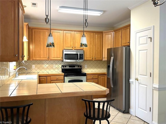 kitchen featuring visible vents, a peninsula, tile countertops, a sink, and appliances with stainless steel finishes
