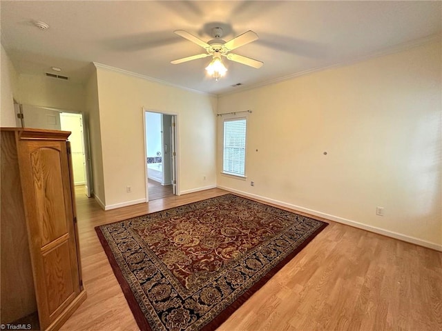 spare room with a ceiling fan, visible vents, light wood-type flooring, baseboards, and ornamental molding