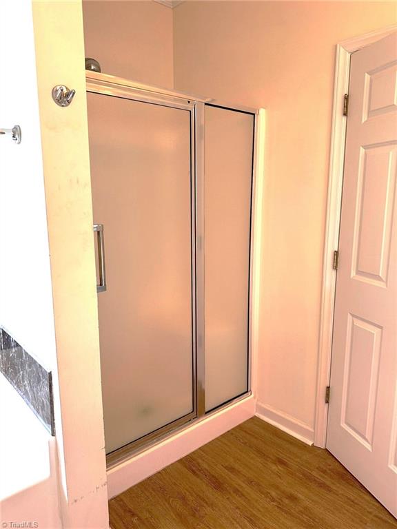 full bathroom with baseboards, a stall shower, and wood finished floors