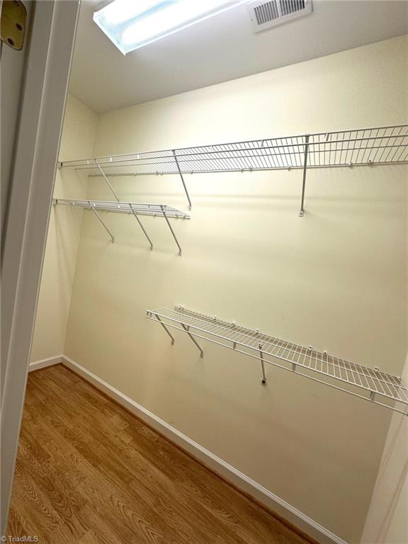 spacious closet featuring visible vents and wood finished floors