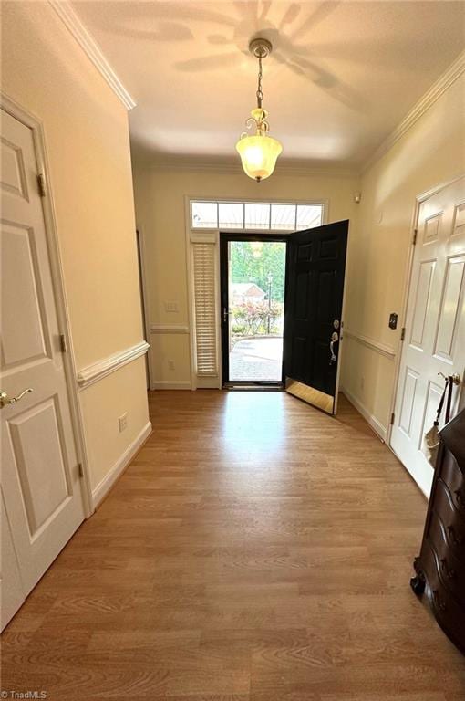 foyer entrance with crown molding, baseboards, and light wood-type flooring