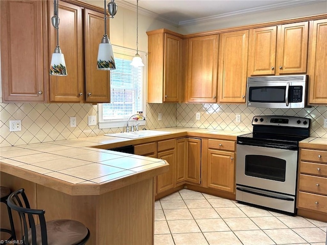 kitchen with backsplash, appliances with stainless steel finishes, a sink, tile counters, and a breakfast bar