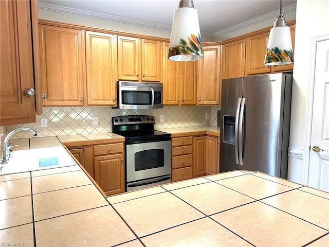 kitchen with appliances with stainless steel finishes, a sink, tile counters, tasteful backsplash, and pendant lighting