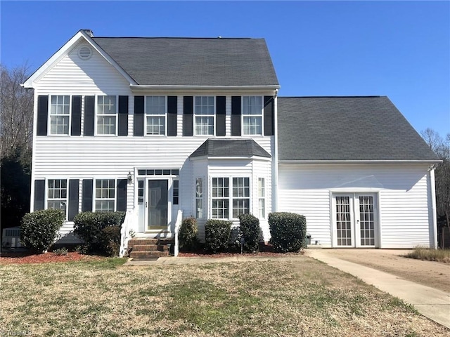 colonial inspired home featuring entry steps, a front yard, and french doors