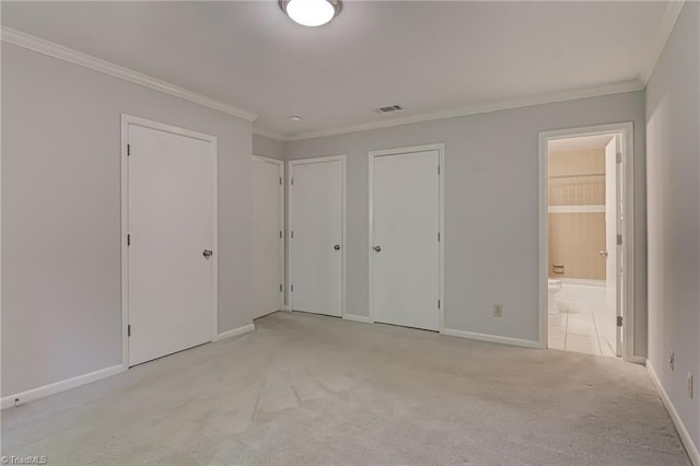 unfurnished bedroom with multiple closets, light carpet, crown molding, baseboards, and ensuite bathroom