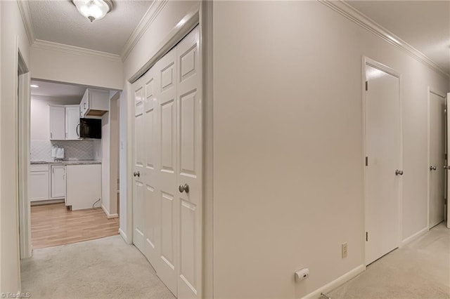corridor featuring light carpet, crown molding, and baseboards