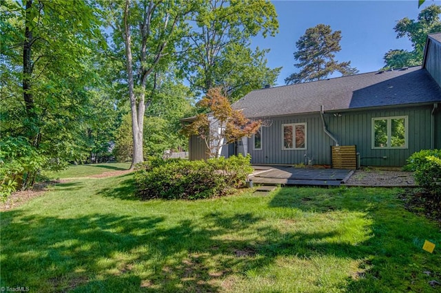 rear view of property with a deck, a lawn, a shingled roof, and board and batten siding