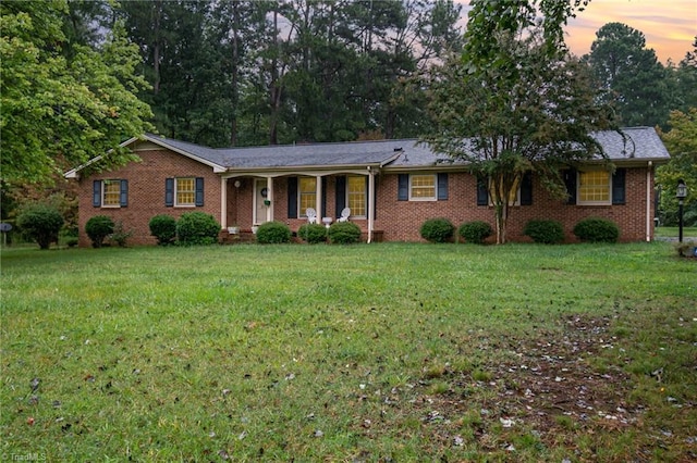 single story home featuring a porch and a yard