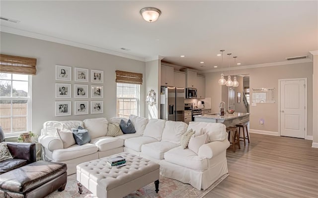 living area with light wood-type flooring, baseboards, visible vents, and ornamental molding