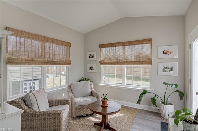 living area with lofted ceiling, wood finished floors, a wealth of natural light, and baseboards