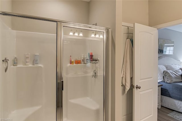 ensuite bathroom featuring wood finished floors, ensuite bath, and a shower stall