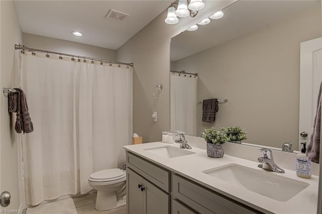 bathroom featuring visible vents, a sink, toilet, and double vanity